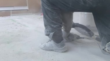 Bir adam beton zeminde duvar kovalayıcısıyla yer altı ısıtması kurmak için ara veriyor.