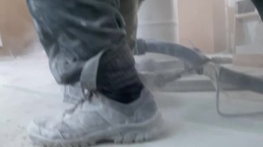 Bir adam beton zeminde duvar kovalayıcısıyla yer altı ısıtması kurmak için ara veriyor.