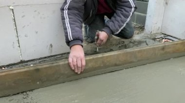 Beton zeminin betonarilmesi. İşçi yer döşemesini beton harç dökerek sağlamlaştırıyor 
