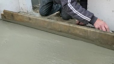 Beton zeminin betonarilmesi. İşçi yer döşemesini beton harç dökerek sağlamlaştırıyor 