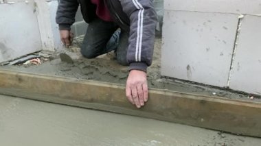 Beton zeminin betonarilmesi. İşçi yer döşemesini beton harç dökerek sağlamlaştırıyor 