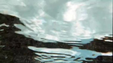 Kristal turkuaz deniz dalgaları kayalık kıyıya çarpar. Su altında çekim yapmak