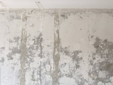 Eski taş duvarın pürüzlü yüzeyinin desenli arka planı çatlaklarla dolu.