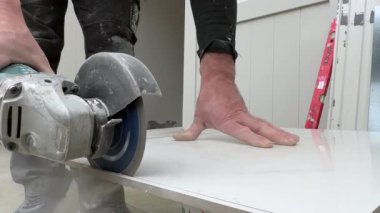 Bir tiler seramik fayansları öğütücüyle keser. İnşaat alanında fayans döşemek.