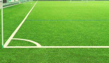 Futbol sahasının bir parçası. Futbol sahasının köşesinde beyaz lekeler var. Beyaz çizgi çimen futbol sahasında çizilmiş. Seçici odak