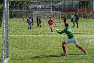 Rotterdam, Hollanda, 30 Ağustos 2025. Yeşil formalı genç futbolcu yeşil sahada takım arkadaşlarıyla yapılan bir futbol antrenmanı sırasında kurtarış antrenmanı yapıyor.