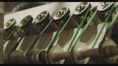 The glass enters the machine on rollers and undergoes a hardening process. The main gears that drive the machine rotate in the frame.