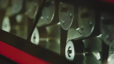 The glass enters the machine on rollers and undergoes a hardening process. The main gears that drive the machine rotate in the frame.