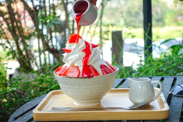 Çilekli Bingsu yanında çilek şurubu ve restorandaki masada taze çilek..