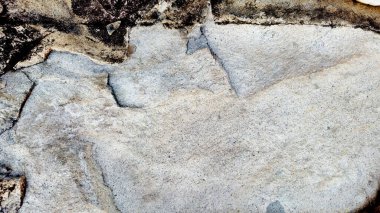 Sert ve organik dokulara sahip doğal bir kaya yüzeyinin yakın çekimi. Arkaplanda kullanmak için ideal tasarım ögeleri.