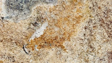 Sert ve organik dokulara sahip doğal bir kaya yüzeyinin yakın çekimi. Arkaplanda kullanmak için ideal tasarım ögeleri.