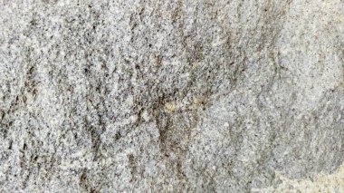 Sert ve organik dokulara sahip doğal bir kaya yüzeyinin yakın çekimi. Arkaplanda kullanmak için ideal tasarım ögeleri.