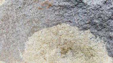 Sert ve organik dokulara sahip doğal bir kaya yüzeyinin yakın çekimi. Arkaplanda kullanmak için ideal tasarım ögeleri.