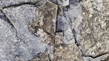 Sert ve organik dokulara sahip doğal bir kaya yüzeyinin yakın çekimi. Arkaplanda kullanmak için ideal tasarım ögeleri.