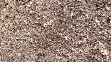 Sert ve organik dokulara sahip doğal bir kaya yüzeyinin yakın çekimi. Arkaplanda kullanmak için ideal tasarım ögeleri.