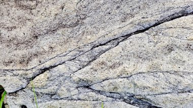 Sert ve organik dokulara sahip doğal bir kaya yüzeyinin yakın çekimi. Arkaplanda kullanmak için ideal tasarım ögeleri.