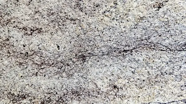 Sert ve organik dokulara sahip doğal bir kaya yüzeyinin yakın çekimi. Arkaplanda kullanmak için ideal tasarım ögeleri.