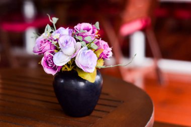 Üflenmiş bir masadaki vazodaki pembe kumaştan çiçekler. Kahve dükkanında, klasik renk tonunda.