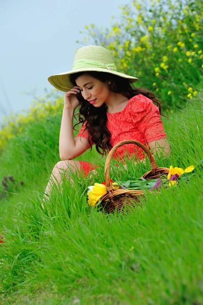 beautiful young woman with a basket of flowers in the garden