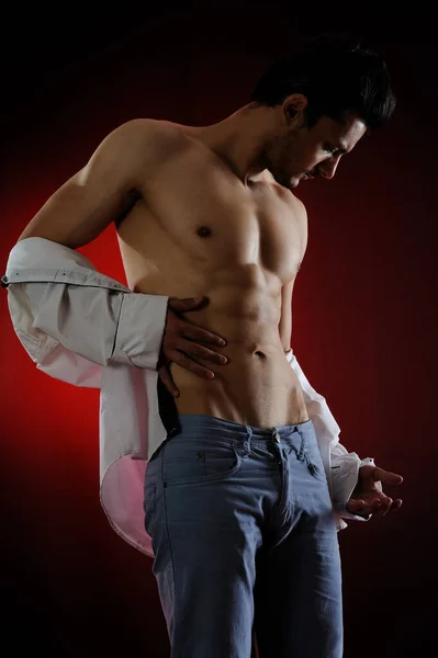 Çıplak gövdeli kaslı bir adam ve siyah arka planda kırmızı bir gömlek.