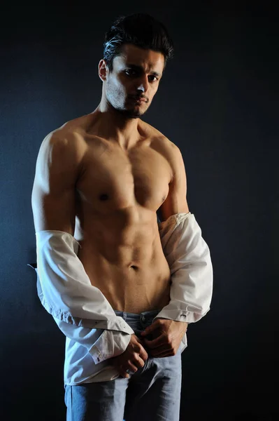 Yakışıklı, üstsüz, kaslı, siyah arka planda duran genç adam.