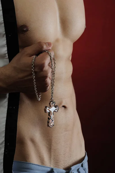 Siyah arka planda haçı olan güçlü, kaslı, vahşi bir adamın portresi.