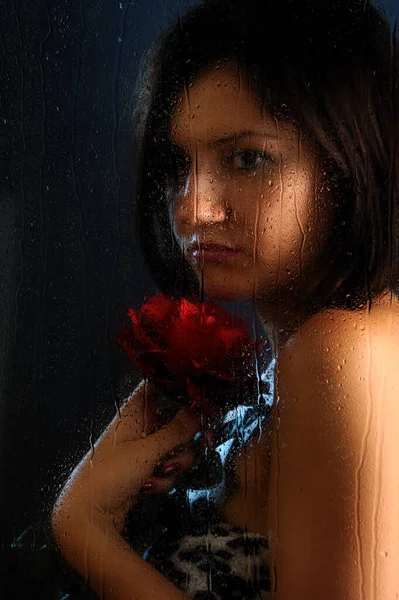 年轻女子抱着红玫瑰晶莹的窗花一滴一滴 — 图库照片