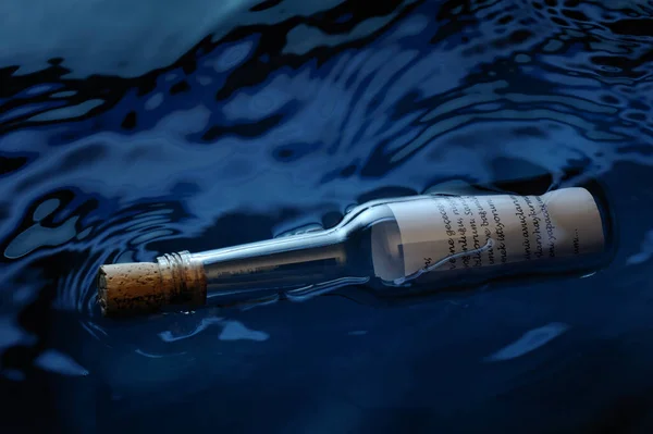 Tıpası kapalı bir cam şişe ve bir dilek kağıdı suyun üzerinde yüzer.