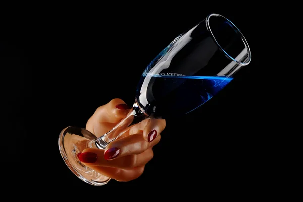 Şarap kadehli, şişeli ve siyah arka planda mavi sıvılı bir kadın. yakın plan.