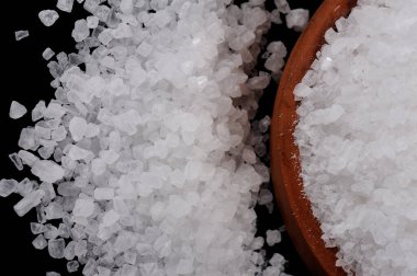 Deniz tuzu kristalleri siyah arkaplanda kil çömlek içinde