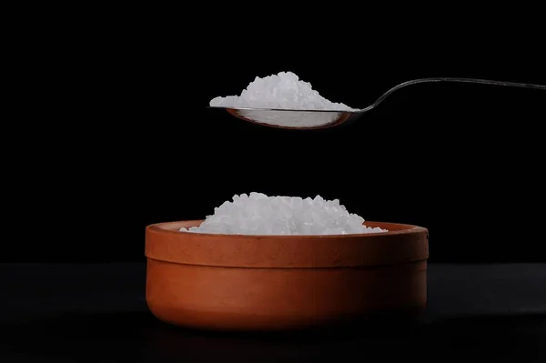 黒地に土鍋の塩結晶とステンレススプーン — ストック写真