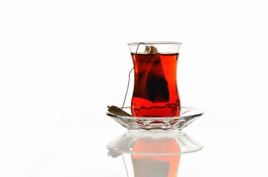 İçinde çay poşeti olan çay fincanı, cam bir tabakta.