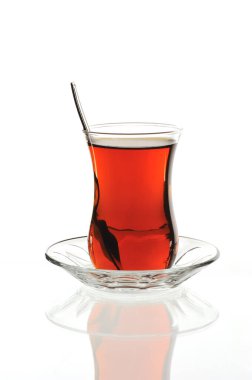 Beyaz arka planda cam bir tabakta klasik Türk çay bardağı.
