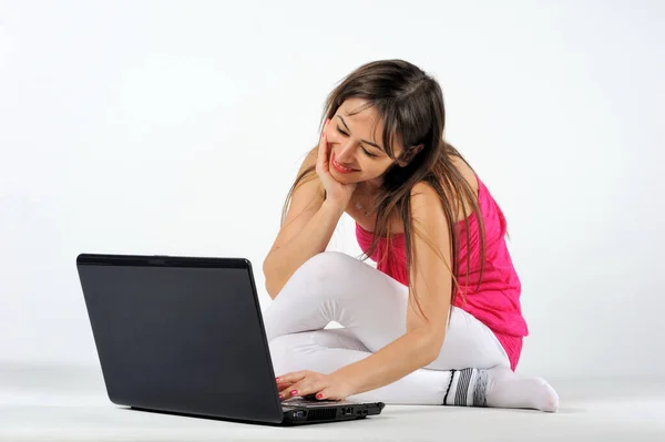 Beyaz arka planda dizüstü bilgisayarı olan genç bir kadın.