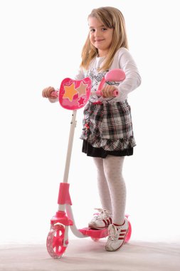 Beyaz arka planda pembe scooter 'ı olan güzel küçük kız.