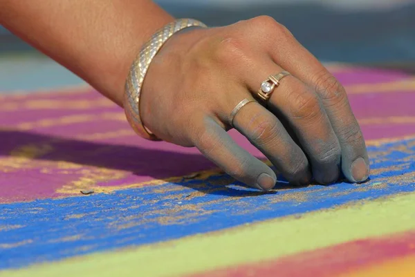 An artist hand at work making beautiful works of art on the street using soft pastel chalk while attending the Madonnari festival