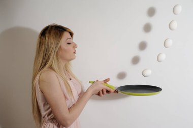 Güzel kız tavayla havadan düşen yumurtaları yakalıyor.