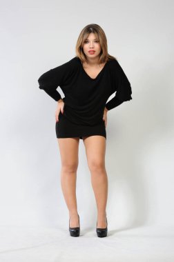 Beyaz arka planda siyah elbiseli güzel bir kadının tam boy portresi.