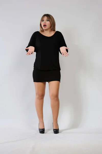 Surprised young woman in a black dress on a white background