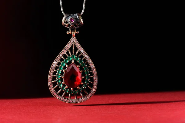 镶嵌宝石的珠宝挂件 底色为深红色和黑色 — 图库照片