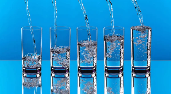 Mavi arka planda akan suyla dolu bardaklar