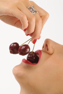 Beyaz arka planda kırmızı kirazları tutan kadınların yakın görüntüsü