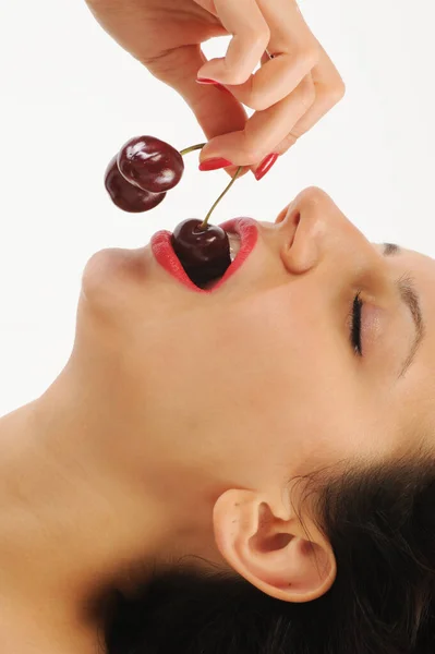 Stock image close-up of a woman eating a red cherries on white background