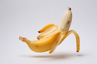 Yakın plan, beyaz zemin üzerinde yarım soyulmuş muz kabukları olan makro..