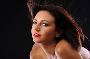 Siyah arka planda poz veren kıvırcık saçlı, uzun koyu renk gözlü güzel bir kadının portresi.