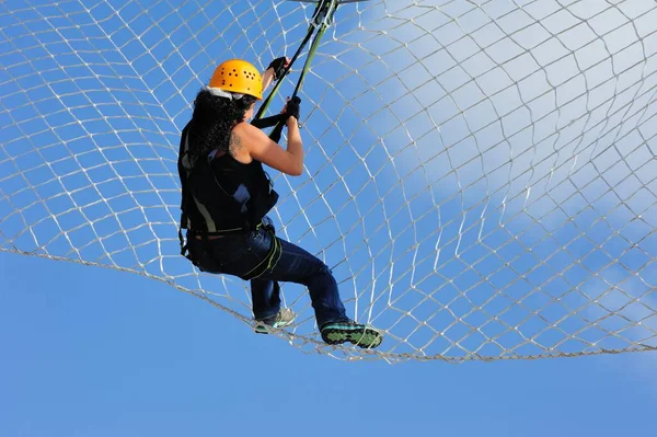 Kız, arka planda bulutlu ve mavi gökyüzü ile tırmanma ve hava yürüyüşü için renkli araba lastikleri üzerinde yürüyor ve egzersiz yapıyor.