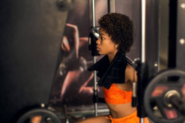 Spor salonundaki elektrikli rafı kullanarak halterci kadın halterleri geriyor. Sağlık ve yaşam tarzı kavramı