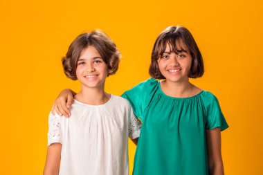 Sarı arka planda gülümseyen iki kız kardeşin portresi. Soğukluk ve dostluk dışında.