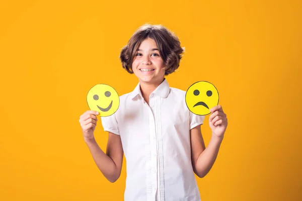 Girl holds sad and happy emoticons in hands. Mental health, psychology and children's emotions concept