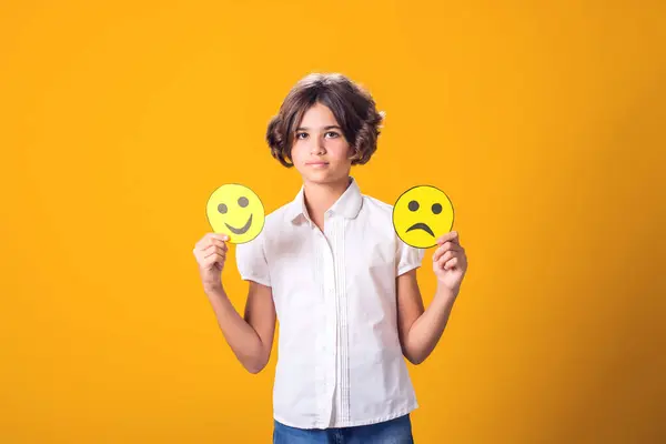 Girl holds sad and happy emoticons in hands. Mental health, psychology and children\'s emotions concept
